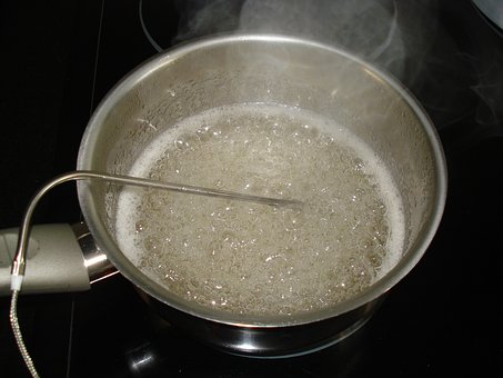 Termometerprob nedsänkt i kokande olja i en kastrull